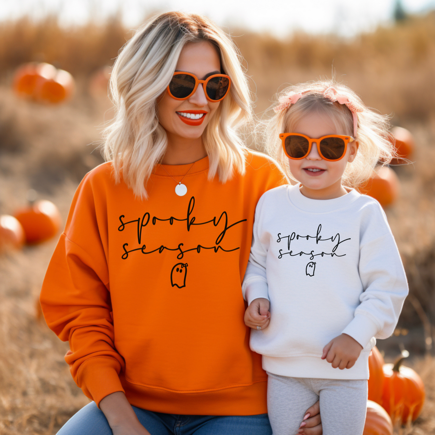 a woman and a little girl sitting on a pumpkin patch