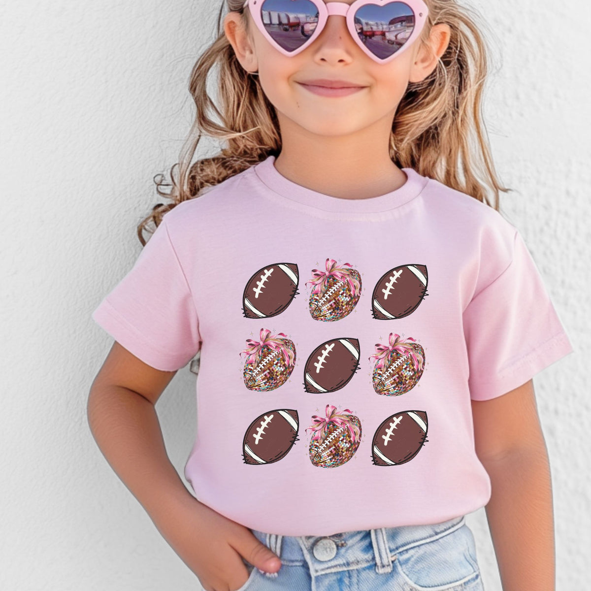 Youth wearing a Pink football and bow grid graphic T-shirt