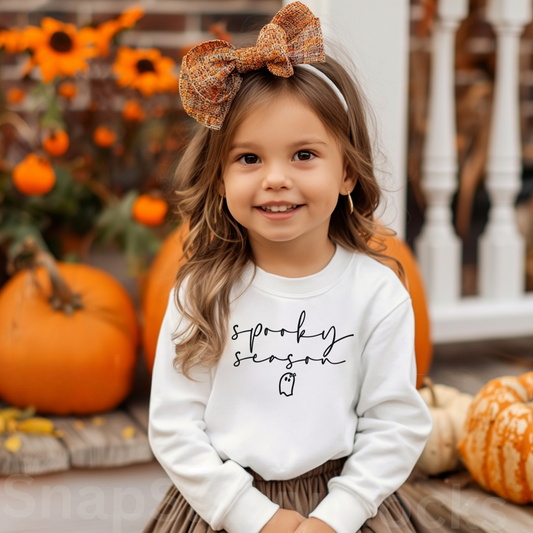 a little girl wearing a white shirt with a brown bow