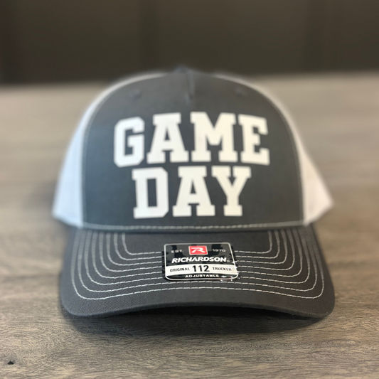 A gray and white baseball cap with the text "GAME DAY" printed on it.
