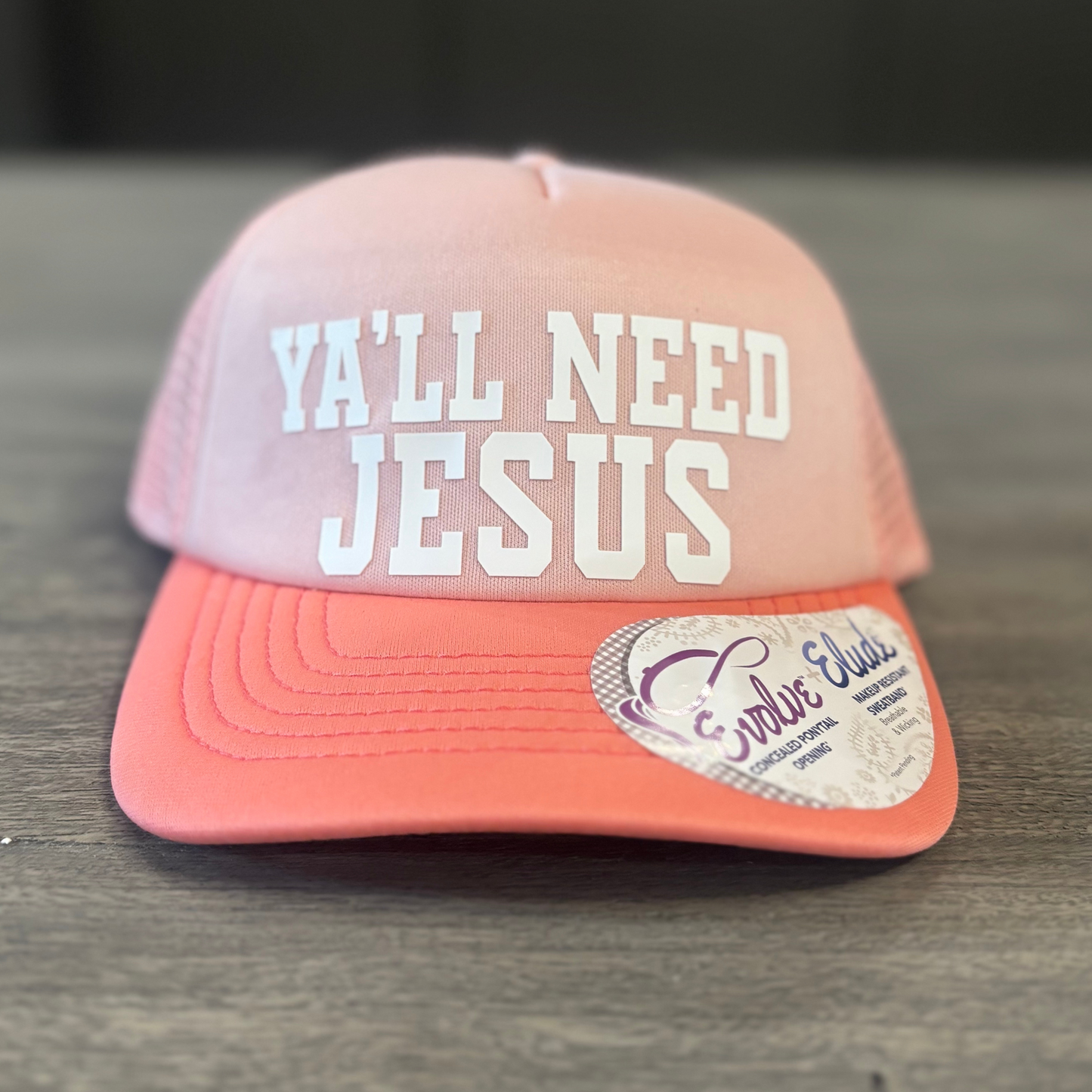 A pink baseball cap with the text "Ya'll need Jesus" printed on it.