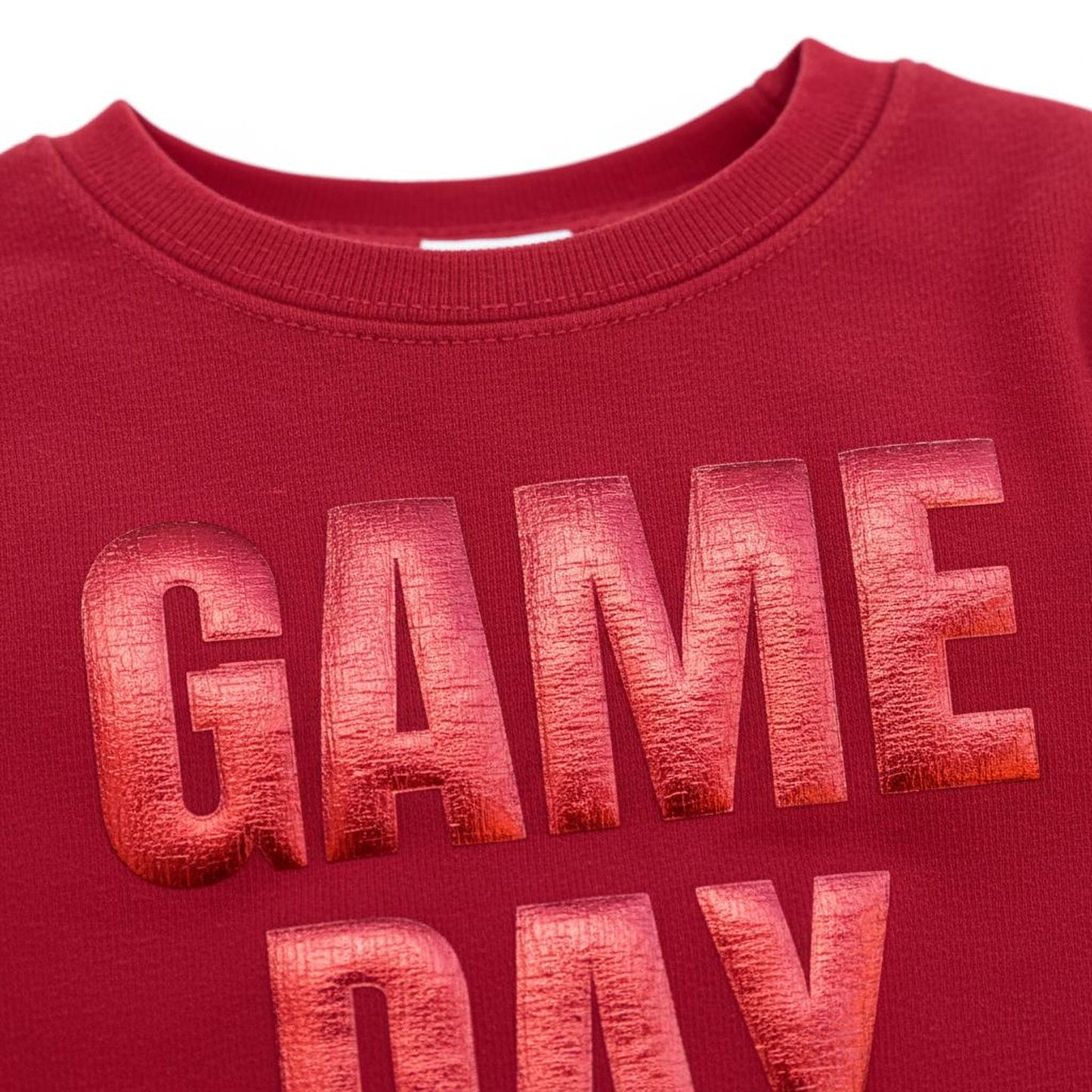 A close-up view of a red t-shirt with the text "GAME DAY" printed on it in a bold, metallic font.