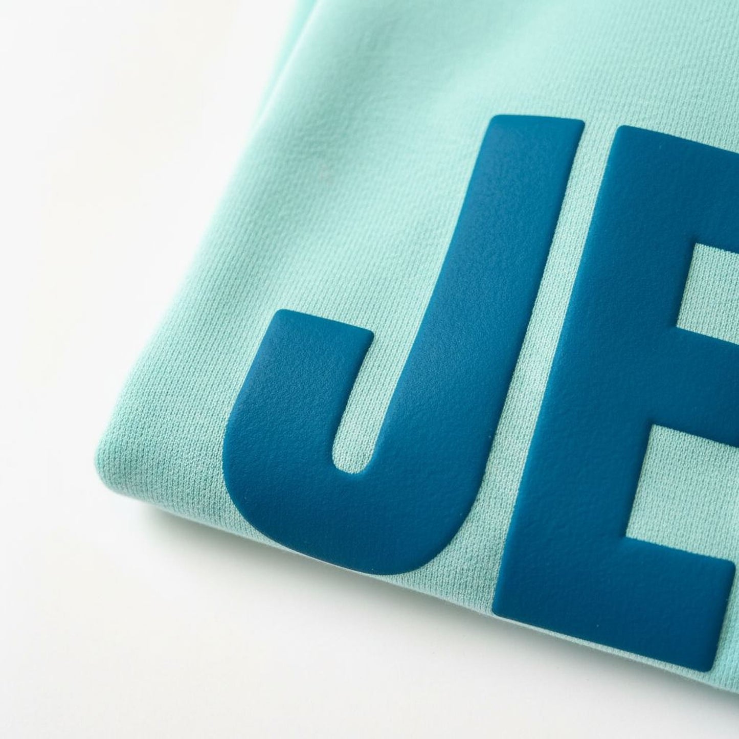 A close-up view of a light blue fabric with large blue letters or text printed on it.