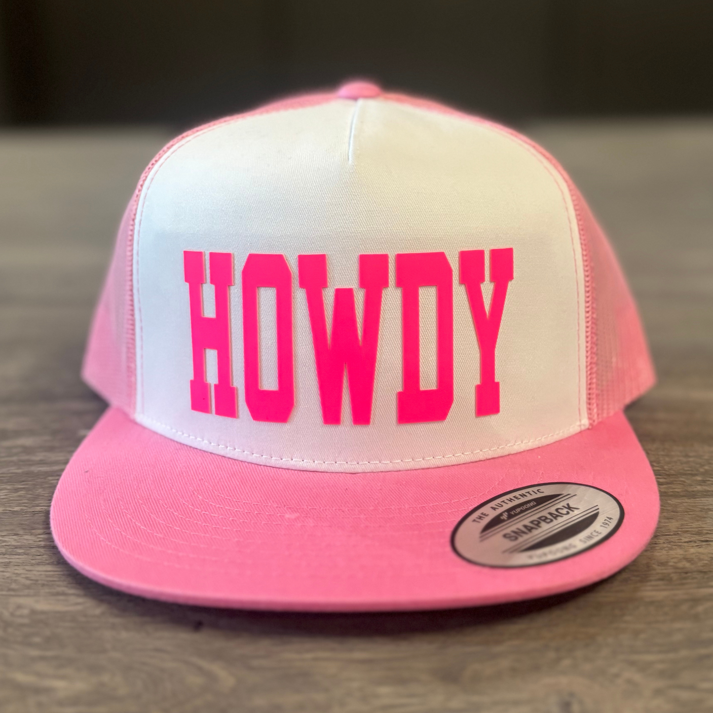 A pink and white baseball cap with the word "HOWDY" printed on it.