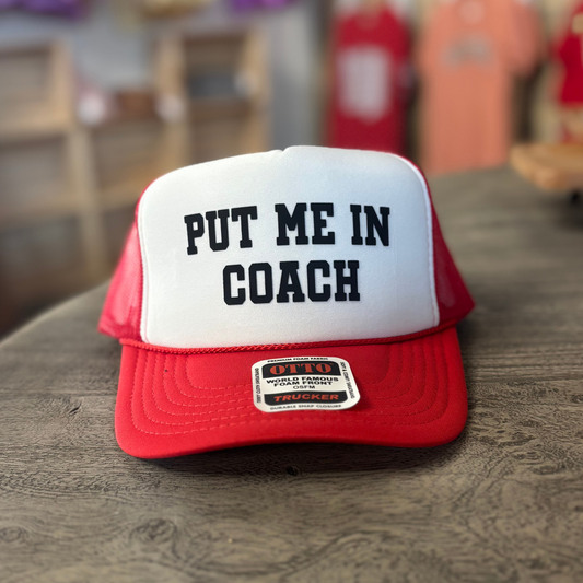 A red and white baseball cap with the text "PUT ME IN COACH" printed on it.