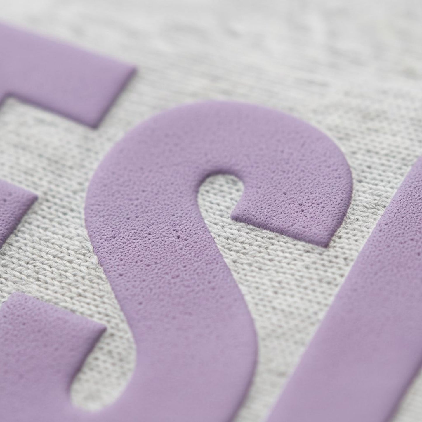 A close-up image of a purple textured letter 'S' on a fabric surface.