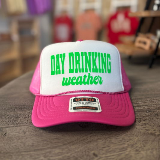 A pink and white baseball cap with the text "DAY DRINKING weather" printed on it.