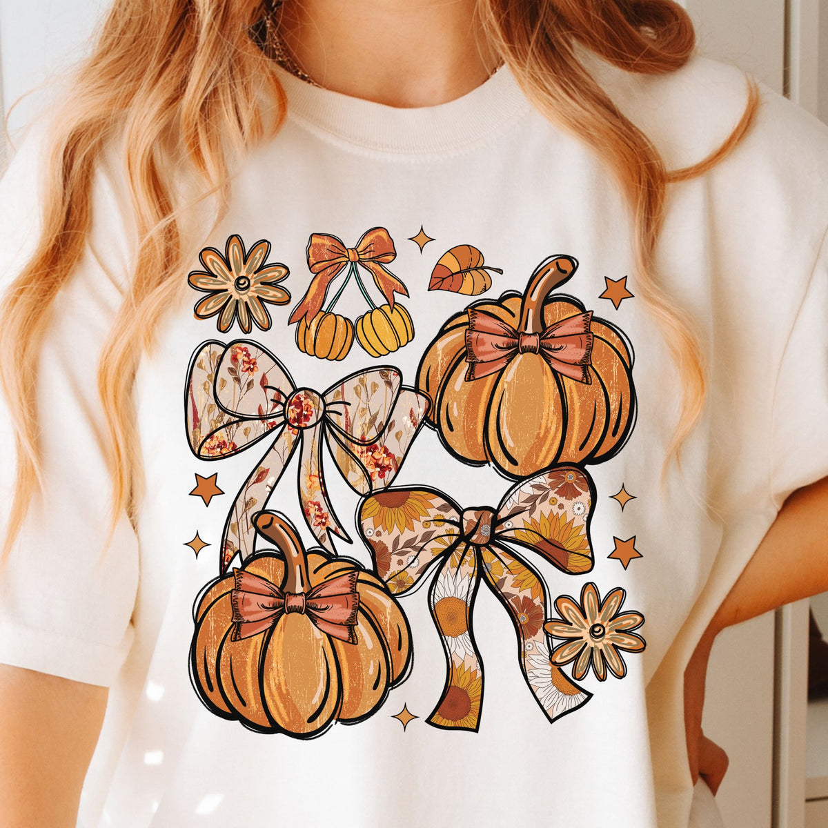 Orange pumpkins, floral bows, daisies, and stars on a Ivory T-shirt