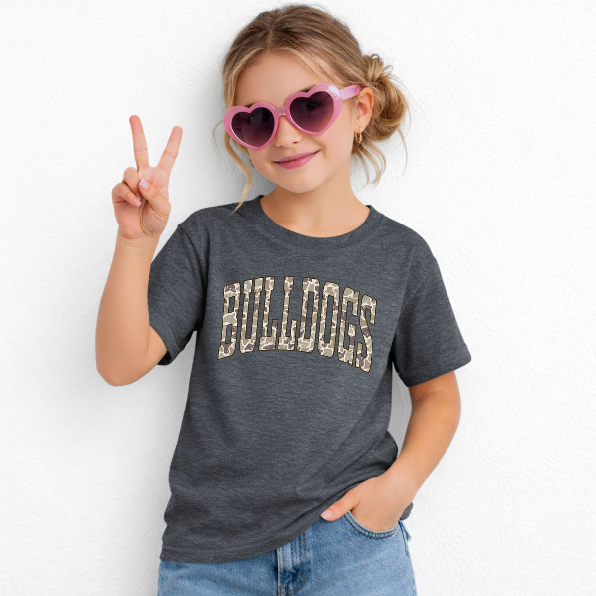 Girl wearing a Dark Heather Gildan 5000B Camo Bulldogs wordmark youth T-shirt
