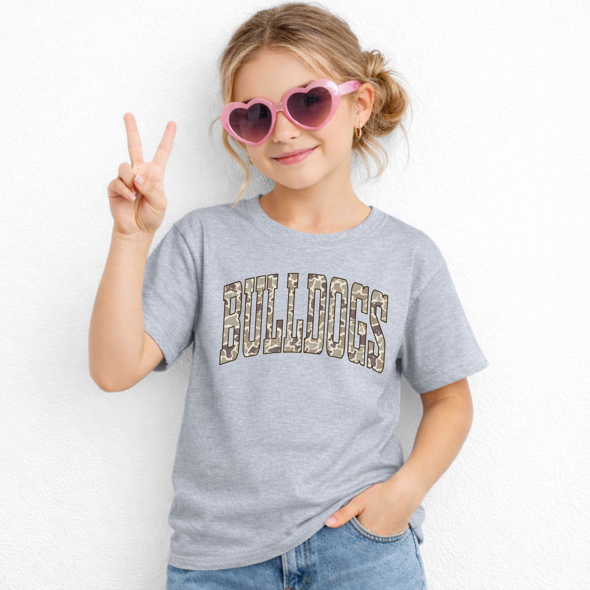 Girl wearing a Grey Gildan 5000B Camo Bulldogs wordmark youth T-shirt