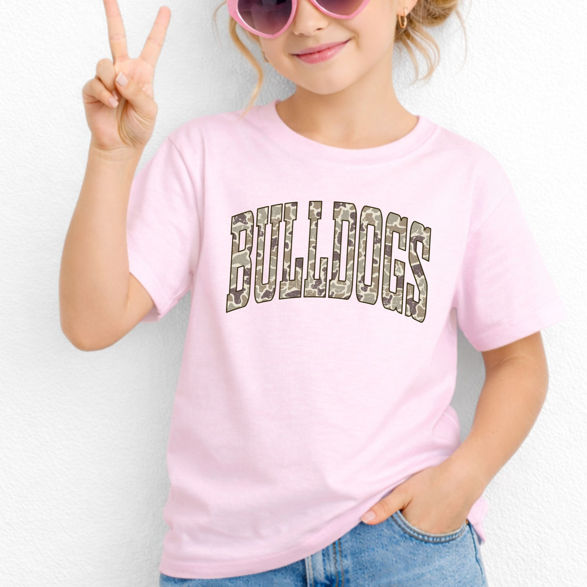 Girl wearing a Light Pink Gildan 5000B Camo Bulldogs wordmark youth T-shirt