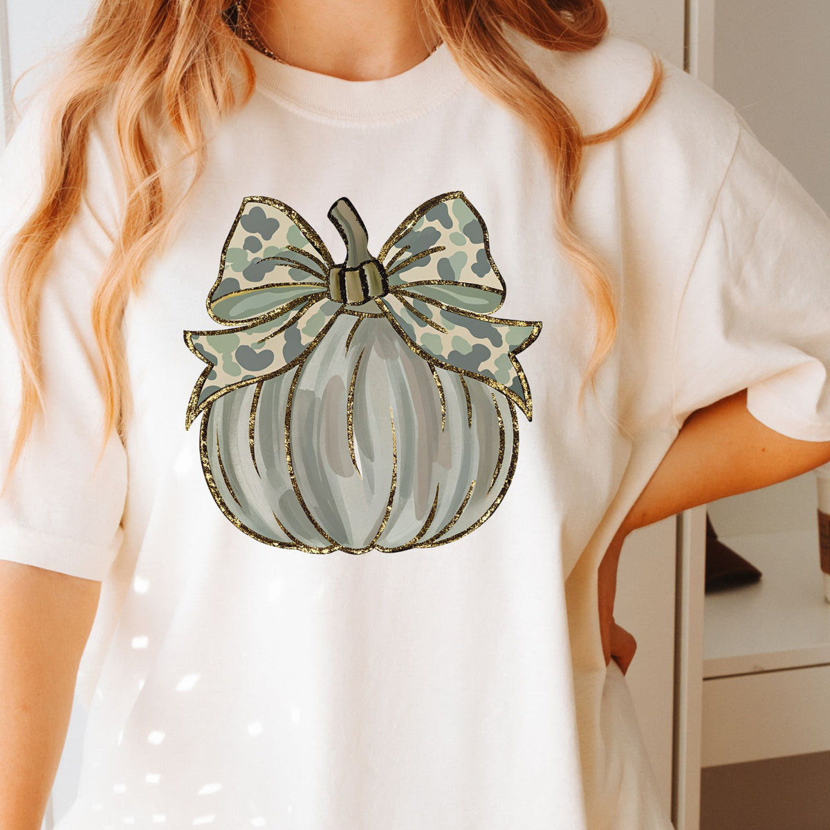 Woman wearing a Ivory Camo Coquette Pumpkin graphic T-shirt