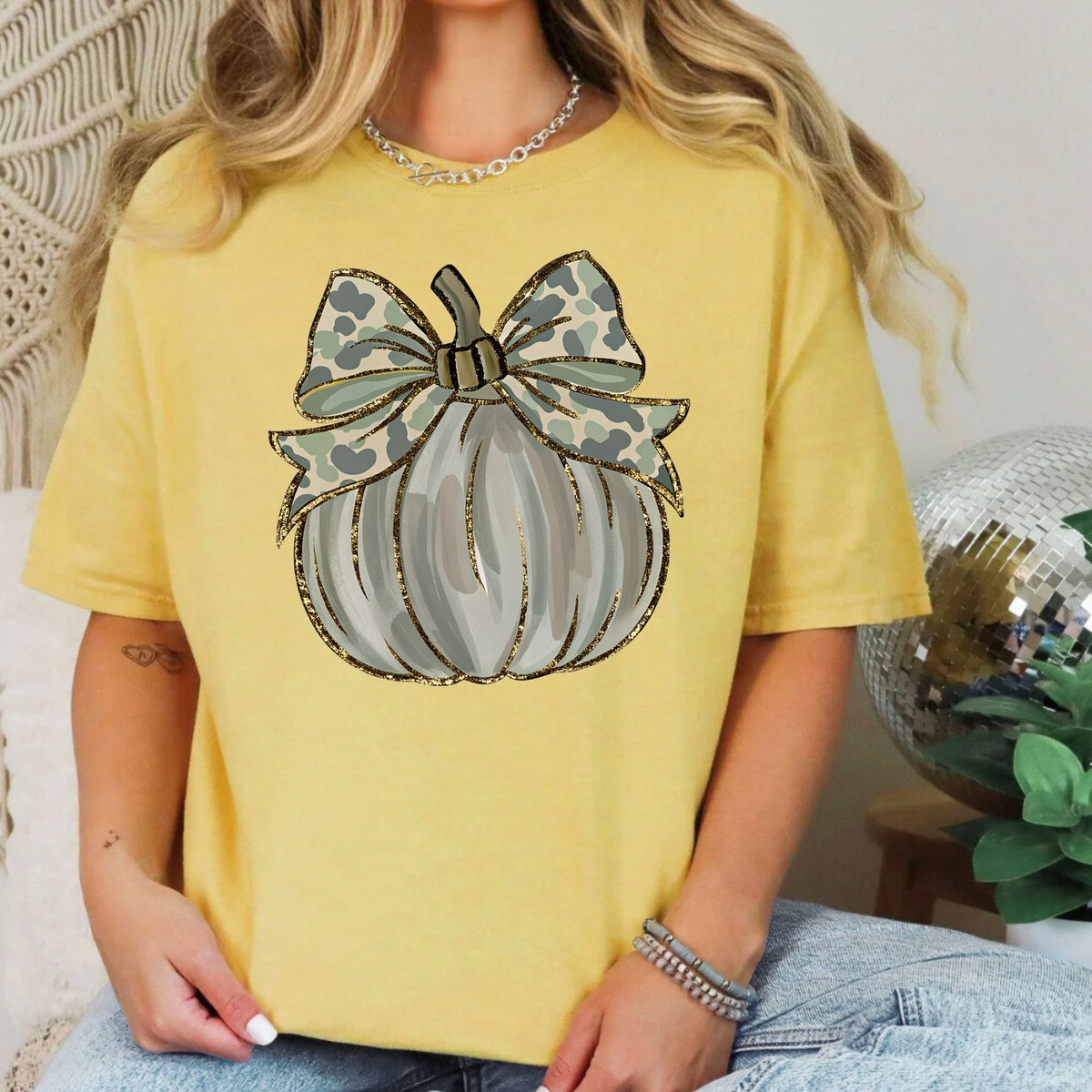 Woman wearing a Mustard Camo Coquette Pumpkin graphic T-shirt