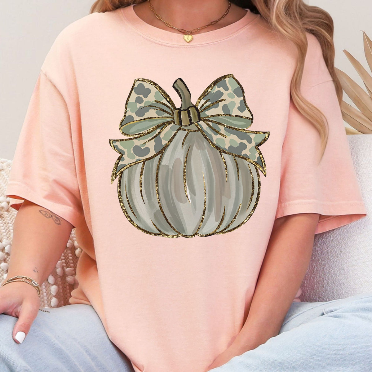 Woman wearing a Peachy Camo Coquette Pumpkin graphic T-shirt