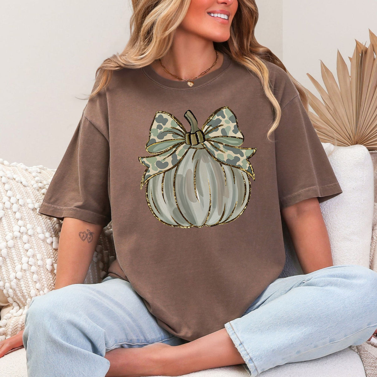 Woman wearing a Yam Camo Coquette Pumpkin graphic T-shirt