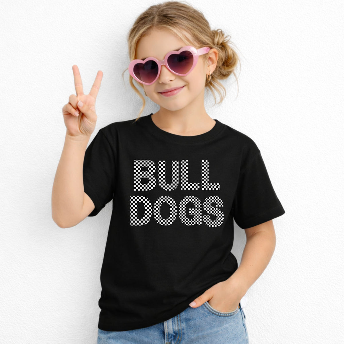 Girl wearing a black Gildan 5000B youth tee with black and white checkered BULL DOGS lettering