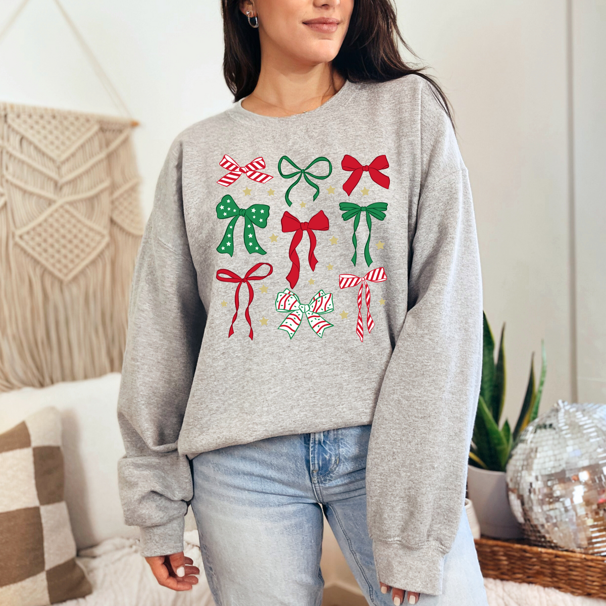 Woman wearing an ash sweatshirt with red and green Christmas bow designs.