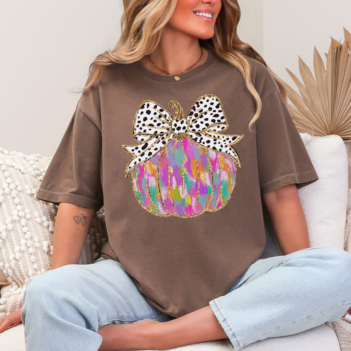 Colorful painted pumpkin with spotted bow on an Espresso Comfort Colors 1717 T-shirt
