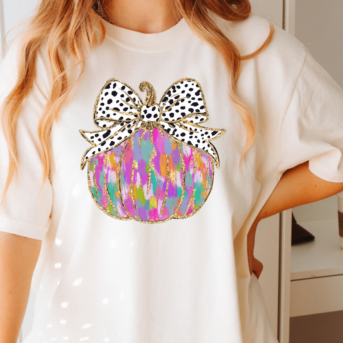 Colorful painted pumpkin with spotted bow on an Ivory Comfort Colors 1717 T-shirt