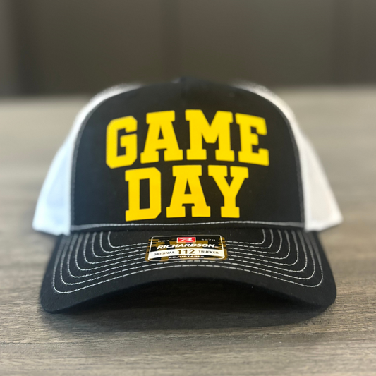 A black and white baseball cap with the text "GAME DAY" printed on it.