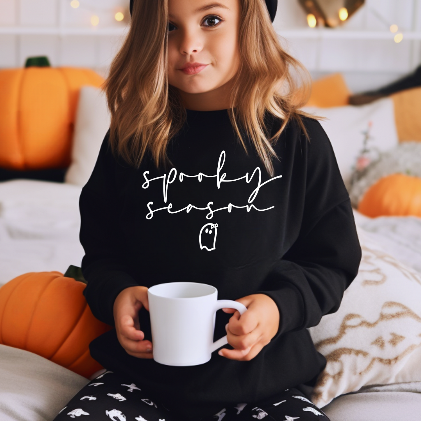 a little girl sitting on a bed holding a coffee cup