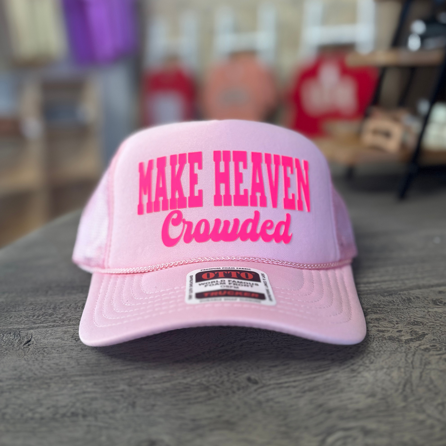 A pink baseball cap with the text "MAKE HEAVEN Crowded" printed on it.