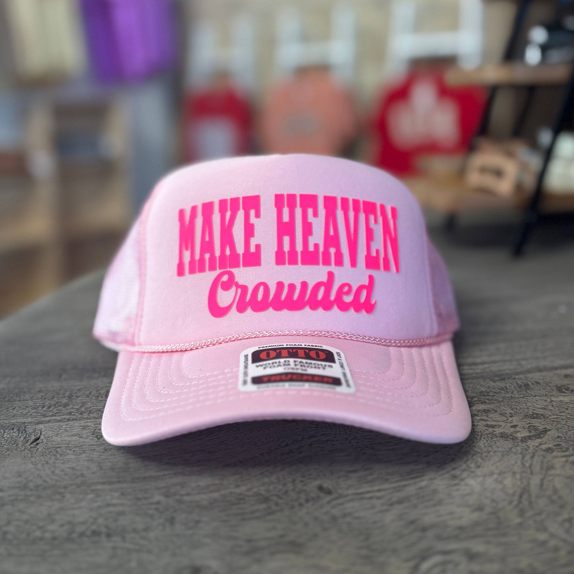 A pink baseball cap with the text "MAKE HEAVEN Crowded" printed on it.