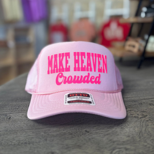 A pink baseball cap with the text "MAKE HEAVEN Crowded" printed on it.
