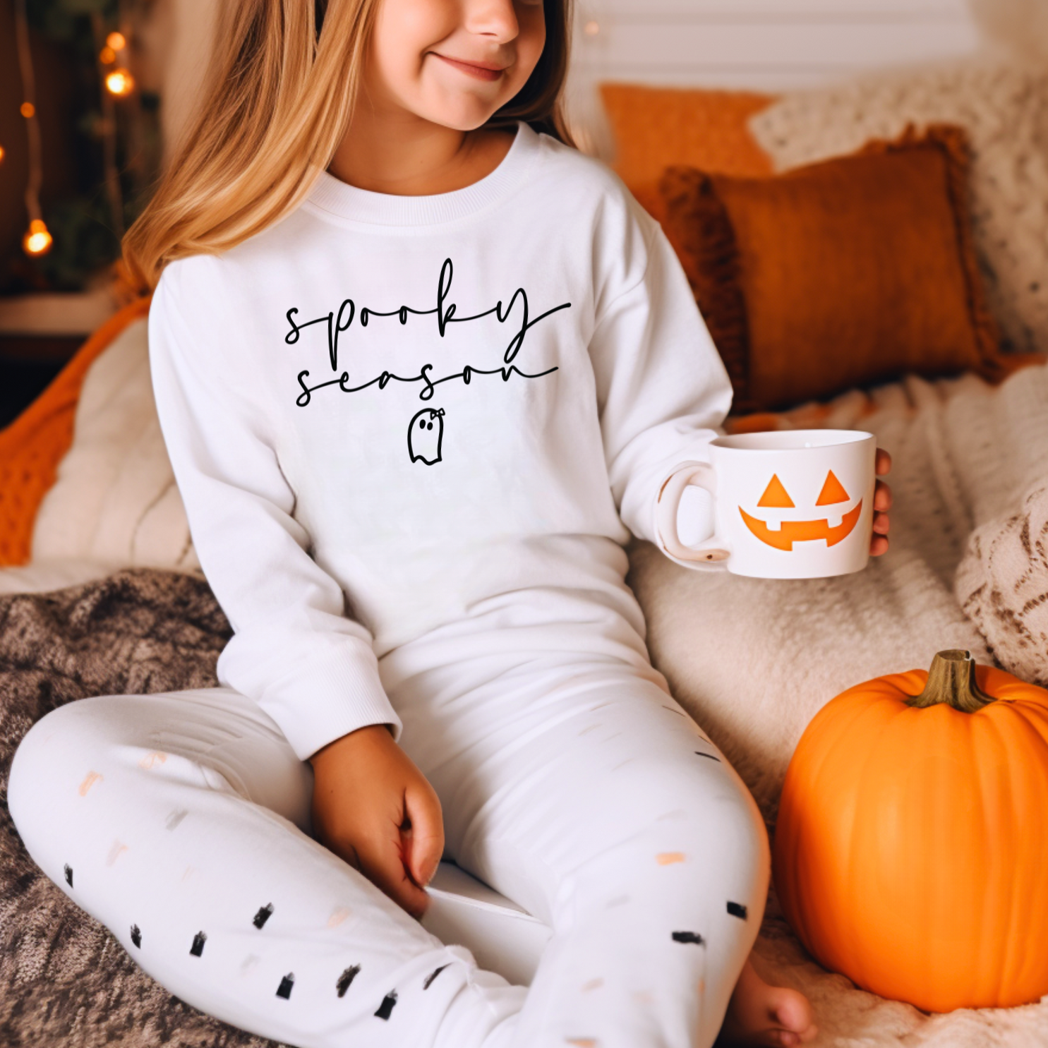 a little girl sitting on a bed holding a cup of coffee