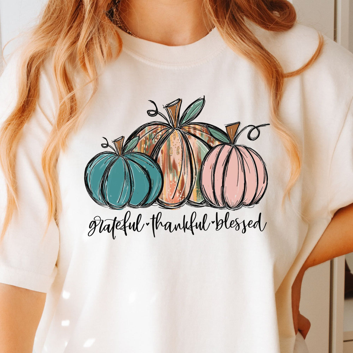 Three painted pumpkins with Grateful Thankful Blessed lettering on a ivory T-shirt