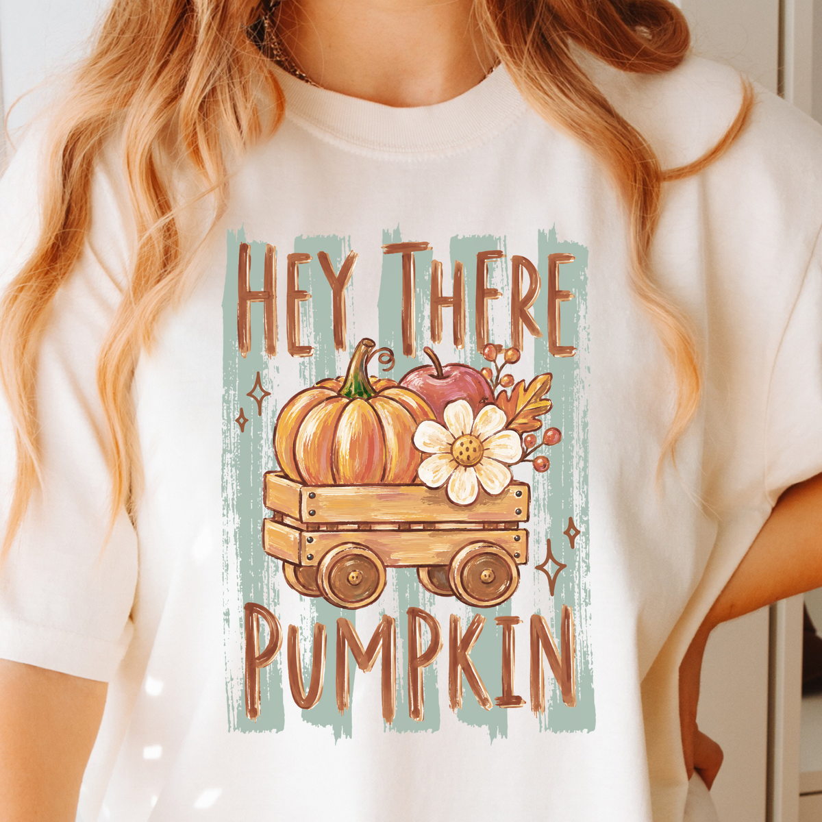 Ivory T-shirt with Hey There Pumpkin lettering, pumpkins and a flower in a wooden wagon
