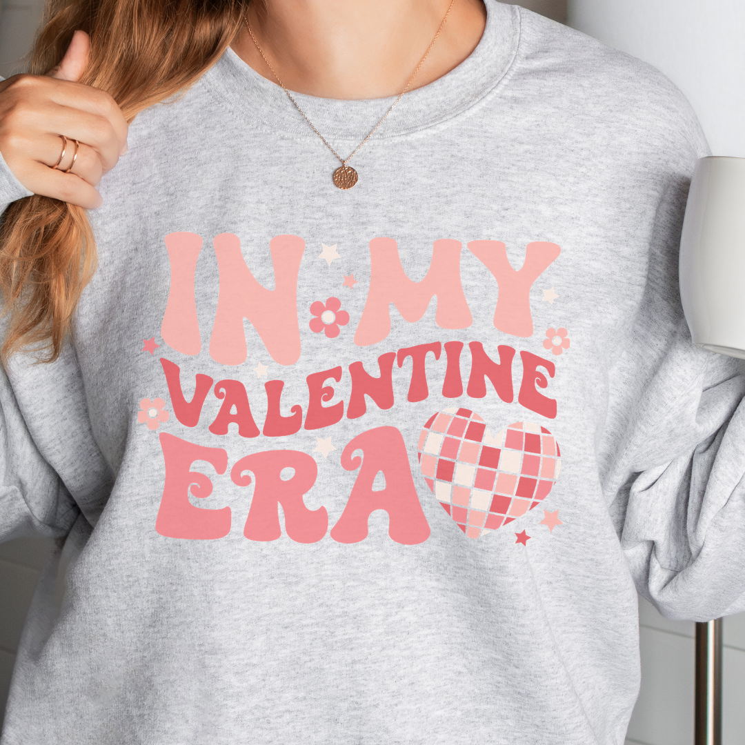 Woman wearing an ash In My Valentine Era graphic sweatshirt.