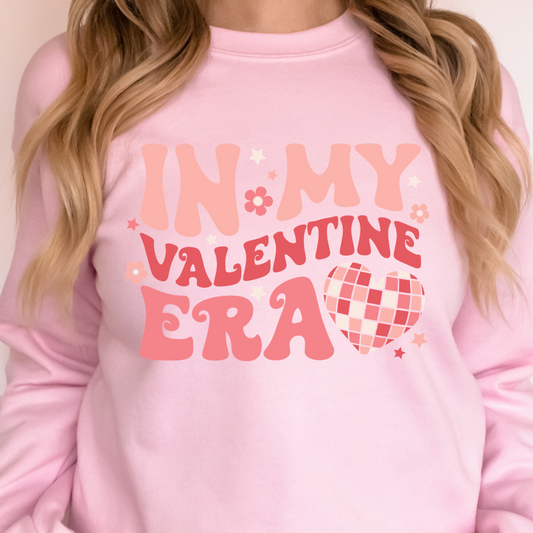 Woman wearing a light pink In My Valentine Era graphic sweatshirt.