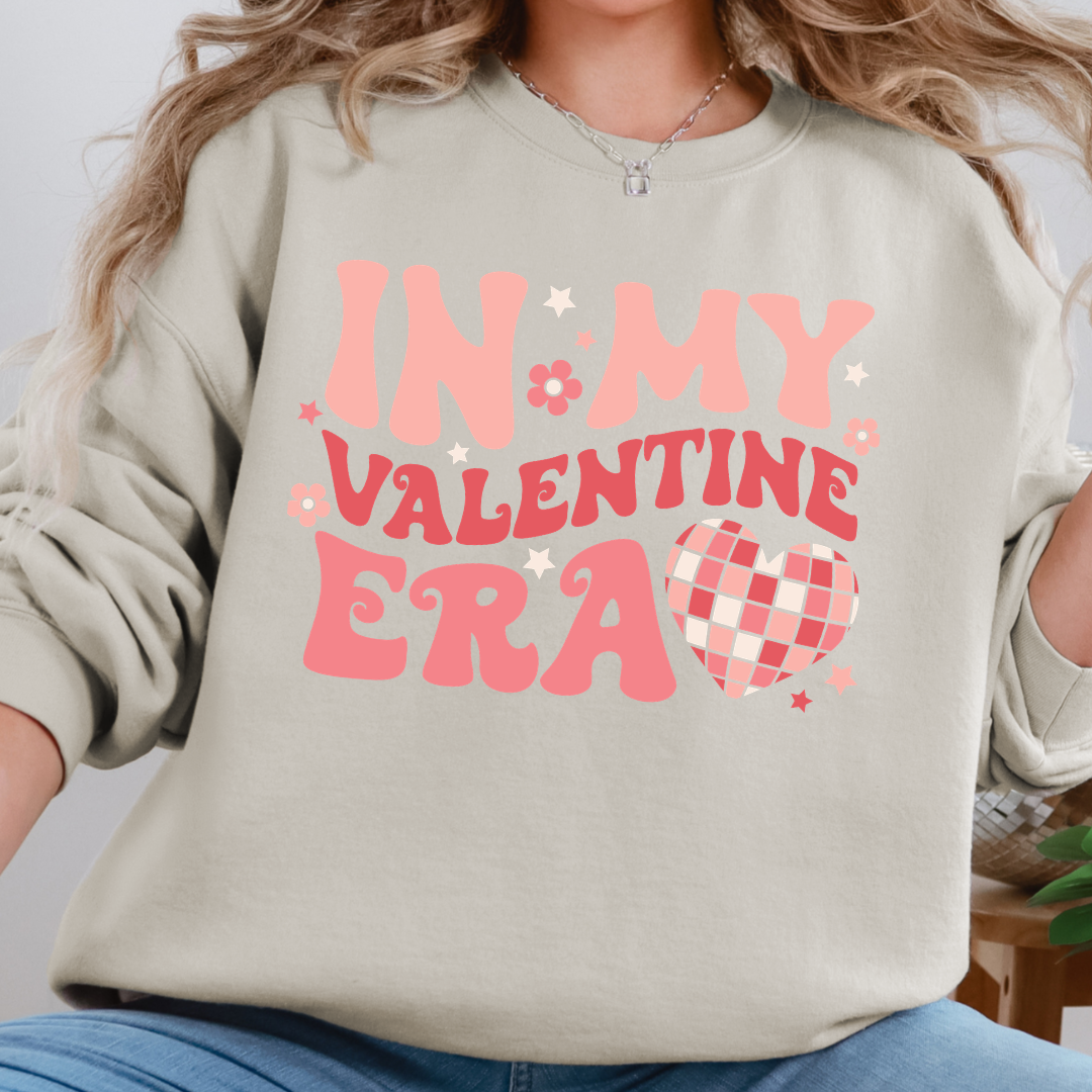 Woman wearing a sand In My Valentine Era graphic sweatshirt.