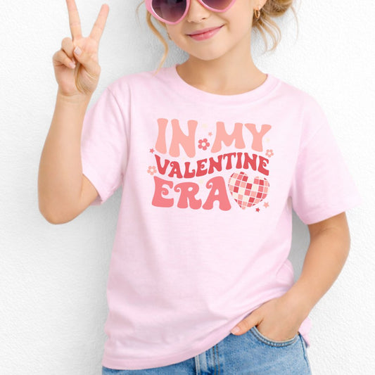 Girl wearing the In My Valentine Era youth T-shirt in Light Pink