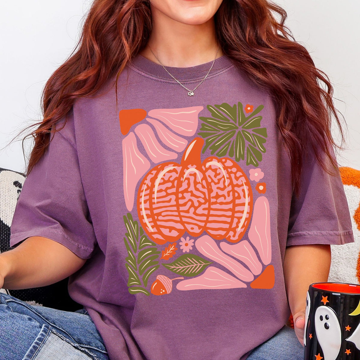 Light pink and orange patterned pumpkin with olive green autumn leaves on a Berry T-shirt