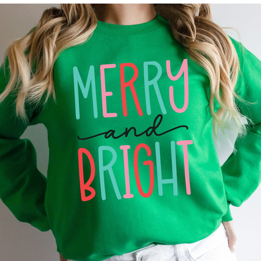 Woman wearing a green sweatshirt with a colorful Merry and Bright design.