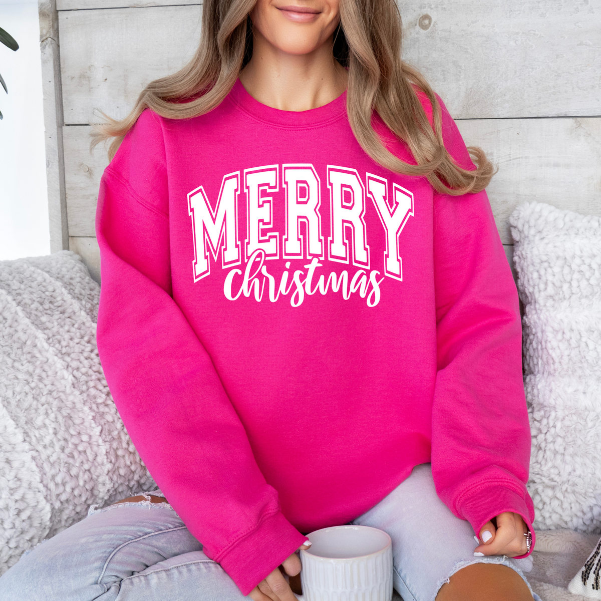 Woman wearing a heliconia sweatshirt with a white Merry Christmas collegiate design.