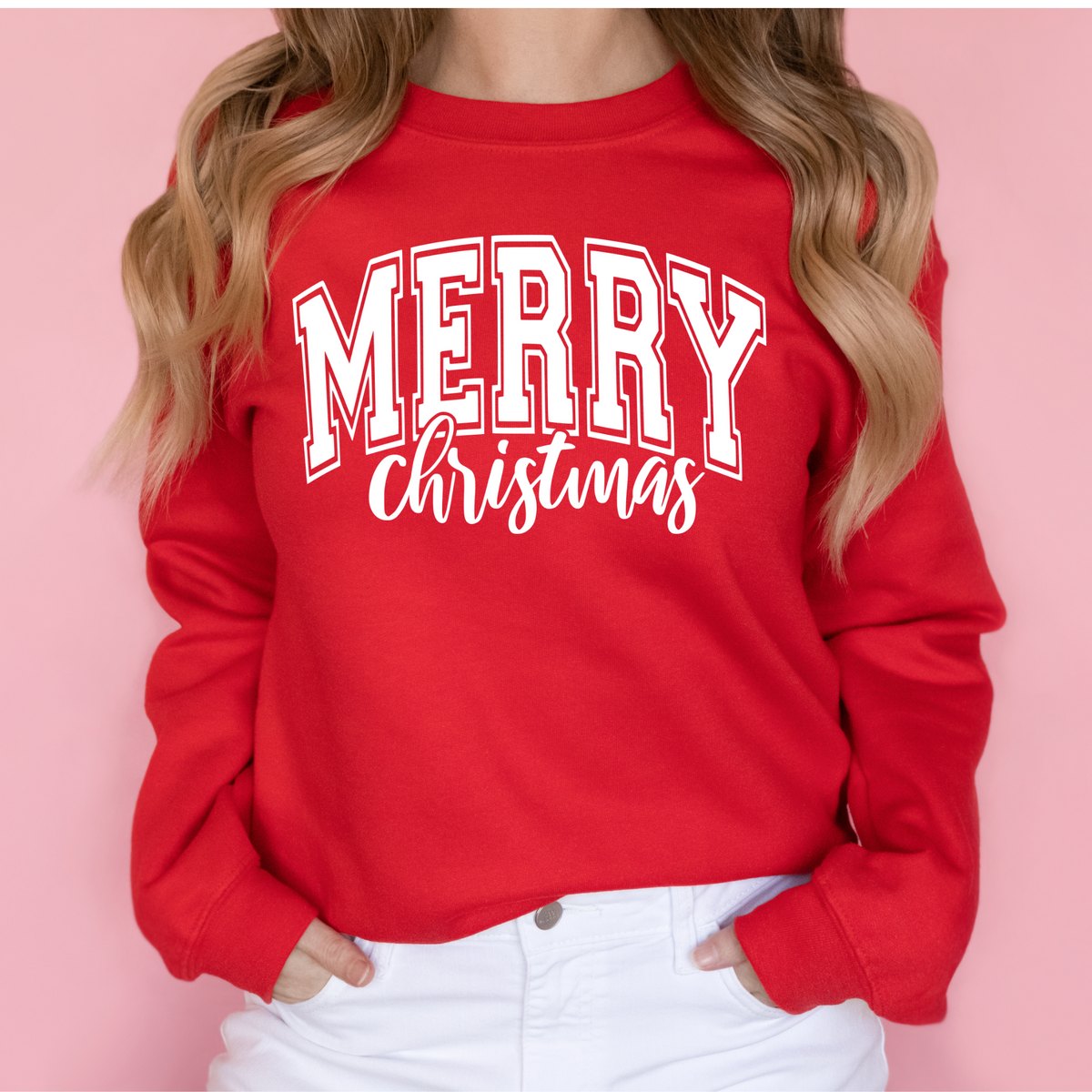 Woman wearing a red sweatshirt with a white Merry Christmas collegiate design.