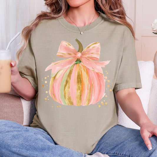Pastel pink, orange, and green pumpkin with gold-look accents and a pink bow on a Khaki T-shirt