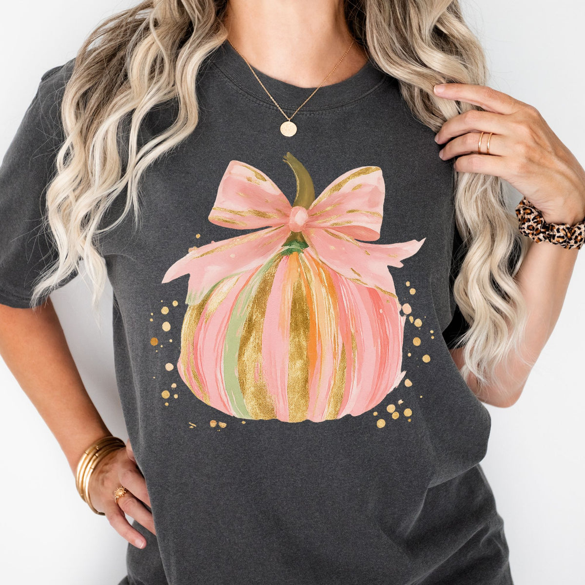 Pastel pink, orange, and green pumpkin with gold-look accents and a pink bow on a Pepper T-shirt