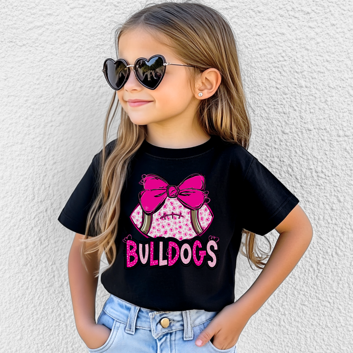 Girl wearing a Black Bella Canvas 3001Y pink leopard football bow Bulldogs youth T-shirt