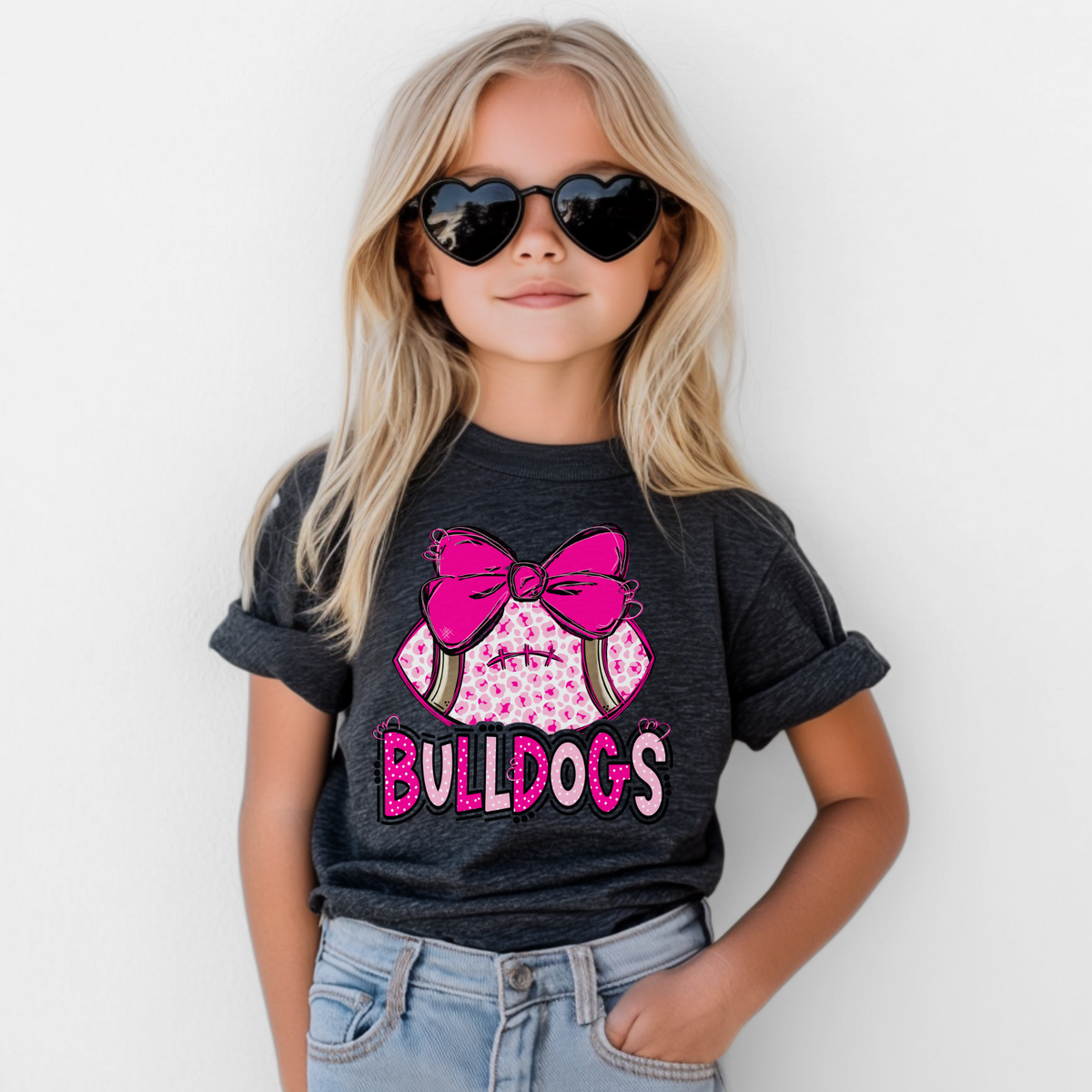 Girl wearing a Dark Grey Bella Canvas 3001Y pink leopard football bow Bulldogs youth T-shirt