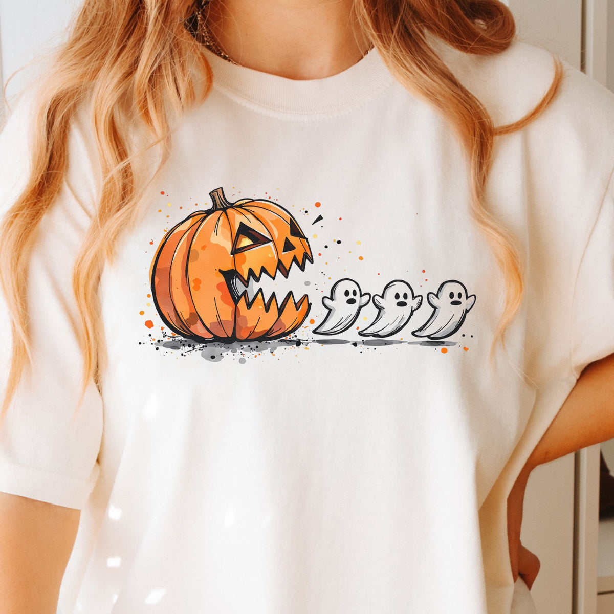 Orange jack-o-lantern chasing three small ghosts on a Ivory T-shirt