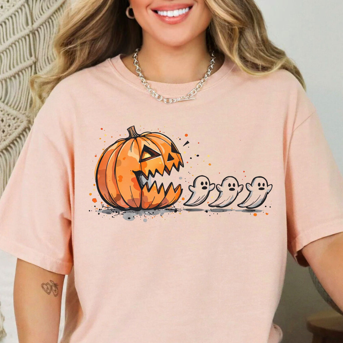 Orange jack-o-lantern chasing three small ghosts on a Peachy T-shirt