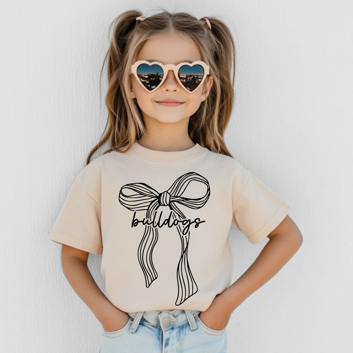 Girl wearing a Natural Bella Canvas 3001Y ribbon bow Bulldogs youth T-shirt