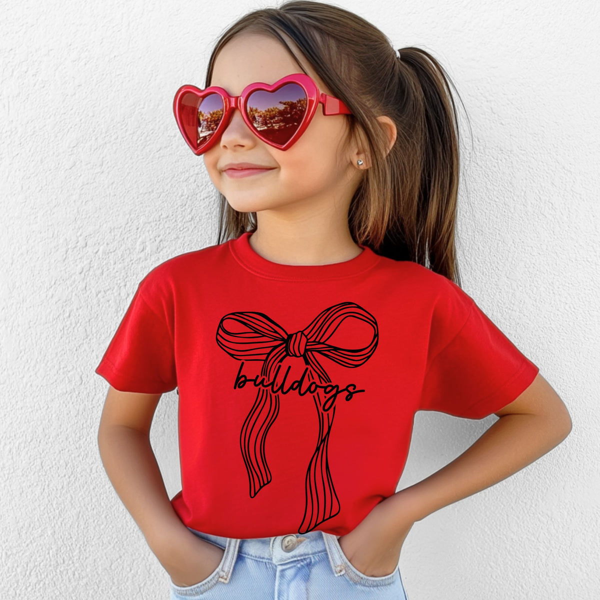 Girl wearing a Red Bella Canvas 3001Y ribbon bow Bulldogs youth T-shirt