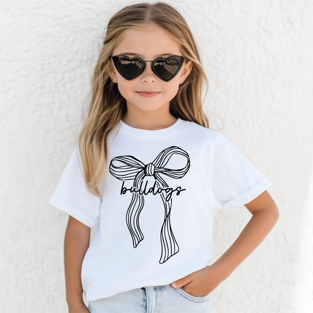 Girl wearing a White Bella Canvas 3001Y ribbon bow Bulldogs youth T-shirt