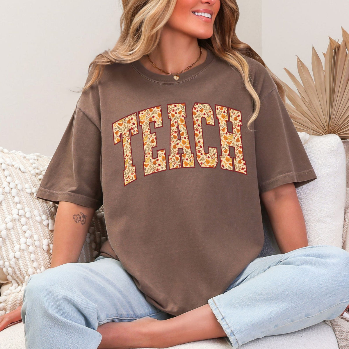 Woman wearing an Espresso TEACH fall leaves graphic T-shirt