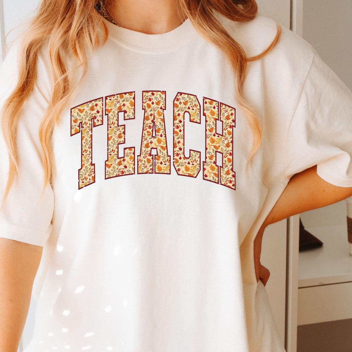 Woman wearing an Ivory TEACH fall leaves graphic T-shirt